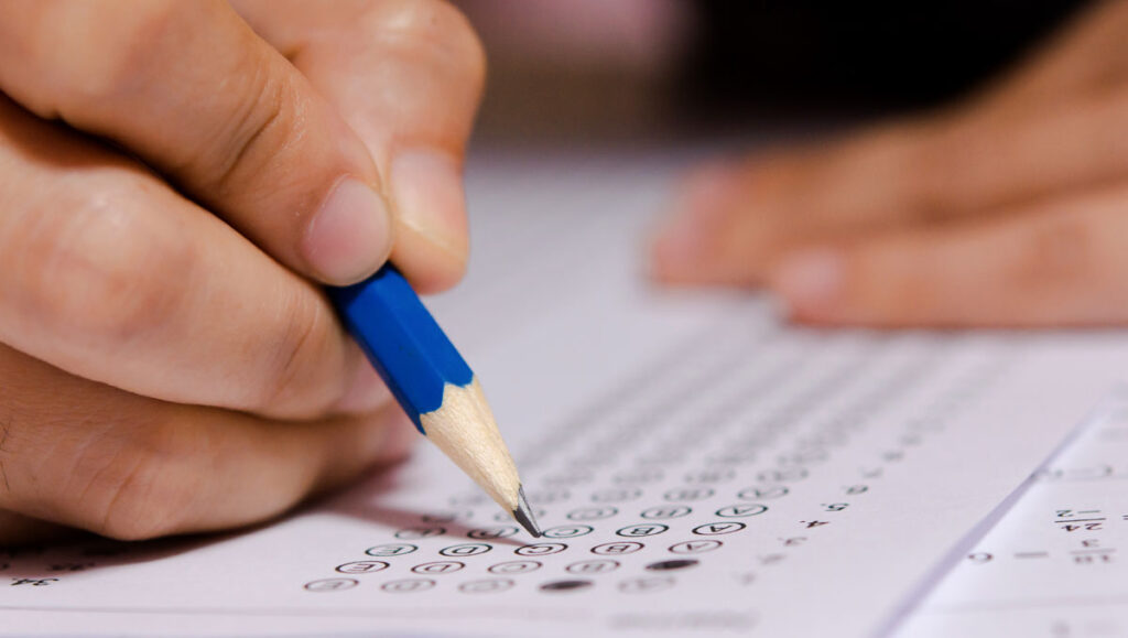 students-hand-holding-pencil-writing-selected-choice-answer-sheets